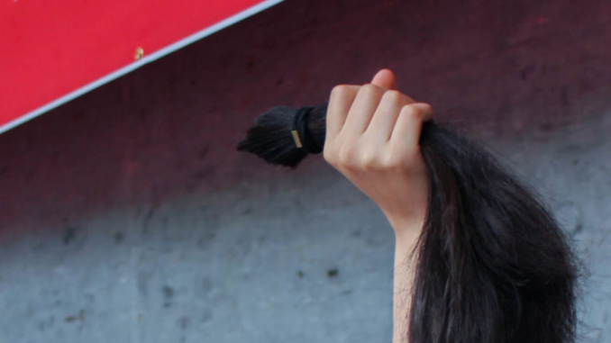 Gaeul Baek holding her cut ponytail during a protest against misogyny on May 2018, Seoul, South Korea._Courtesy of Gaeul Baek and Scena9.